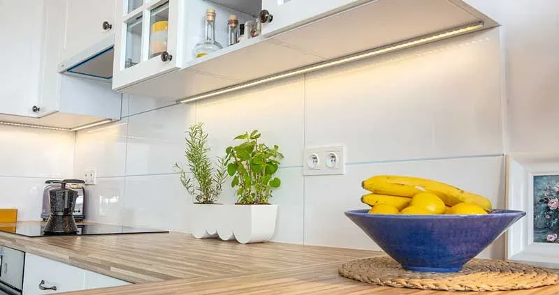 LED-подсветка под верхними шкафами освещает столешницу кухни под дерево